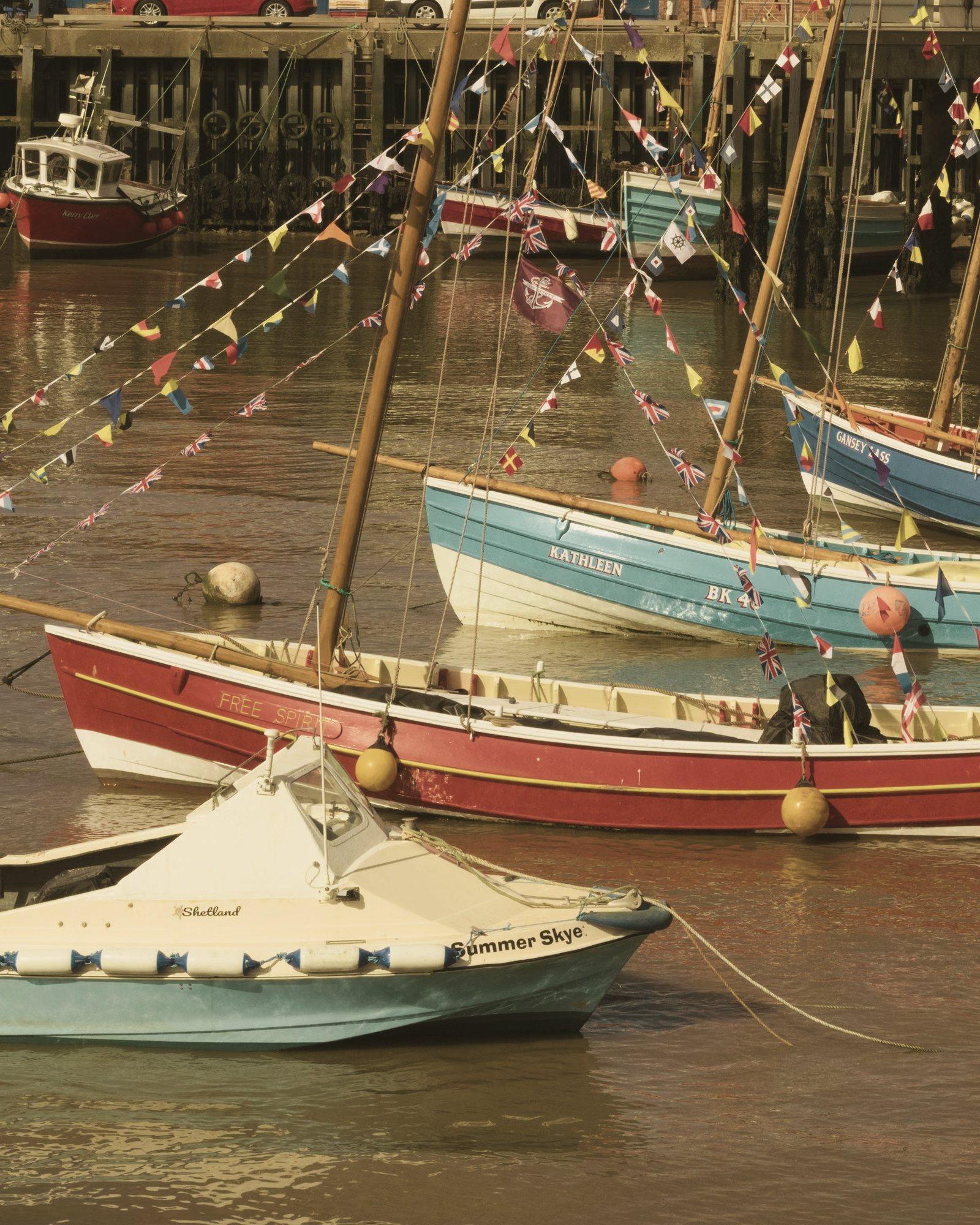 Colourful cobles hung with bunting, moored in Bridlington Harbour on a sunny evening