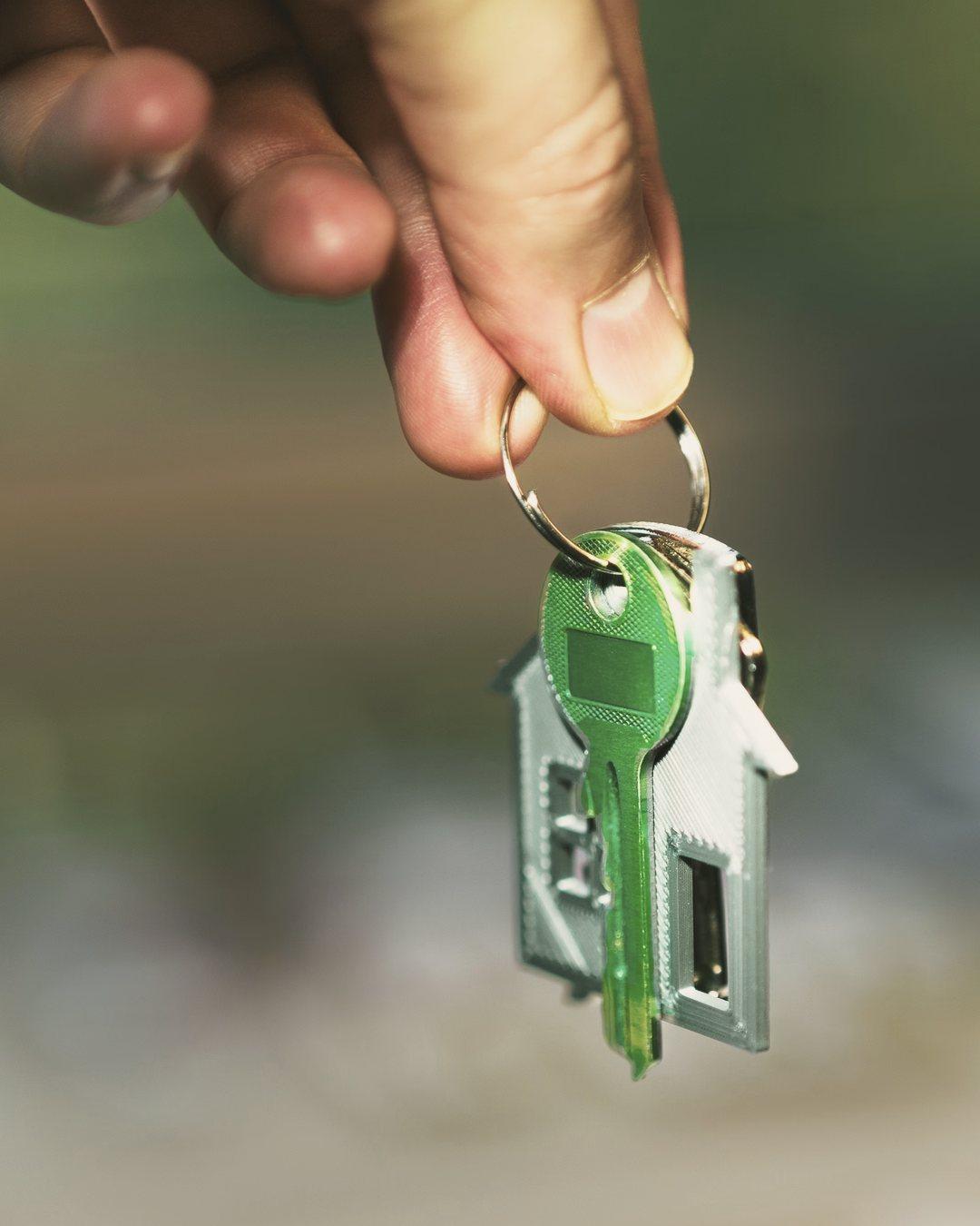 Hand holding a house-shaped keyring with a single key