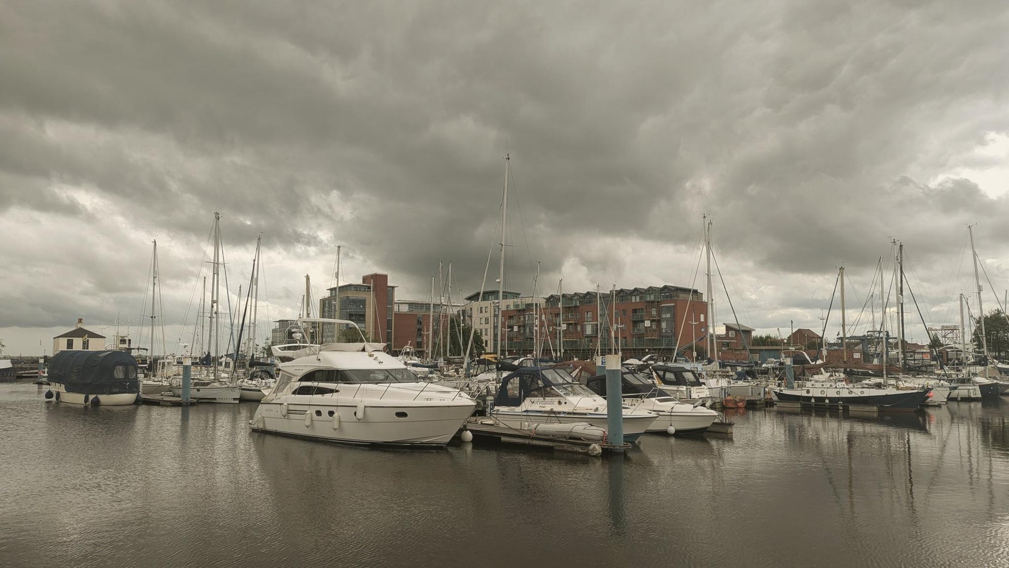 Moored boats beneath heavy grey cloud at Hull Marina